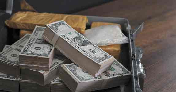 Image of stacks of money in a box with bricks of coke.